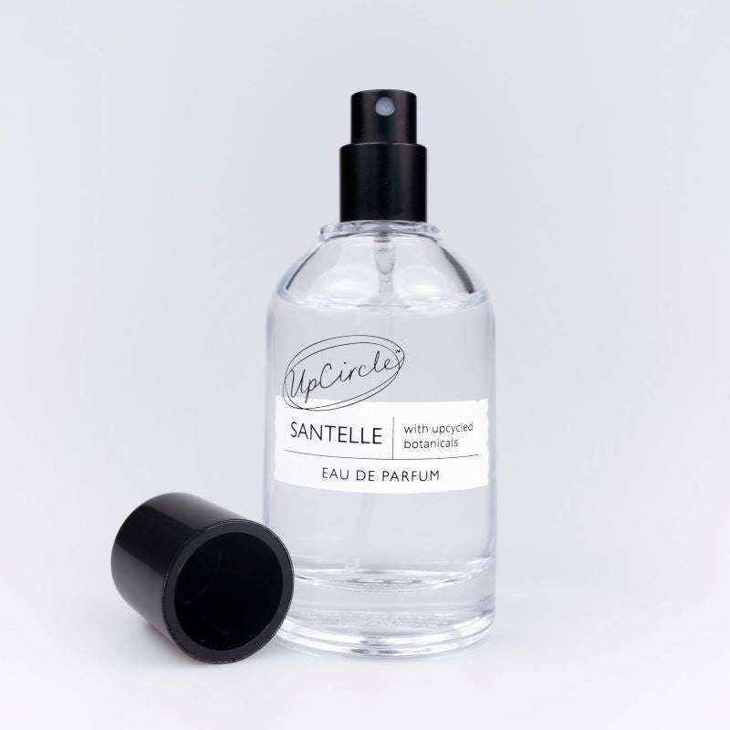 Clear perfume bottle with black spray nozzle and label on a white background