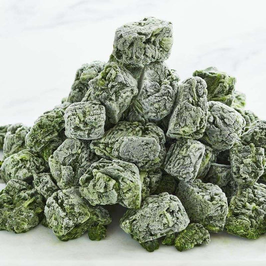 Green frozen frozen spinach leaves stacked on a white background