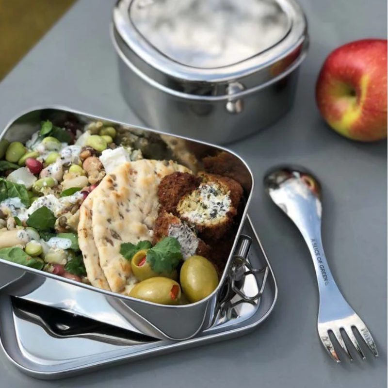 Lunchbox with food, apples, and utensils on a table