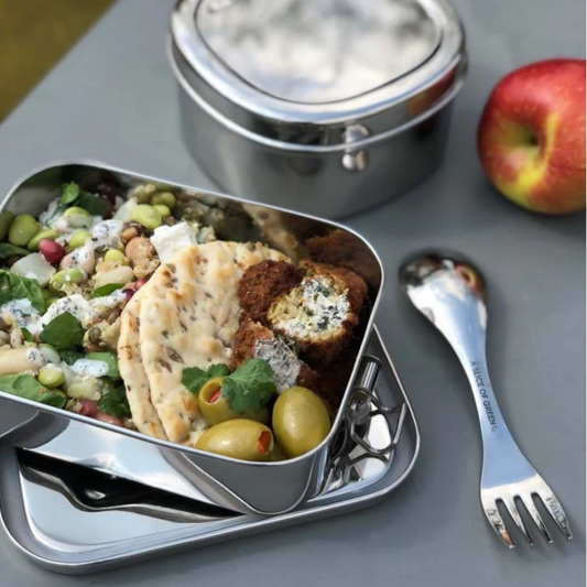 Lunchbox with food, apples, and utensils on a table