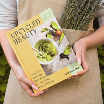 Person holding Upcycled Beauty (HB) book with dried lavender bouquet in apron pocket outdoors in natural light