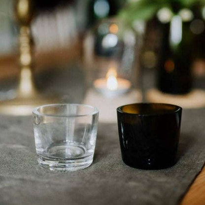 Clear glass and black candle holder on a textured surface with blurred background