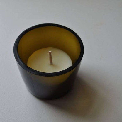 White candle in a black container on a light gray background