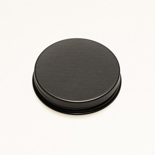A round black metal screw-on lid with a brushed finish and a ribbed outer edge, shown on a plain white background.