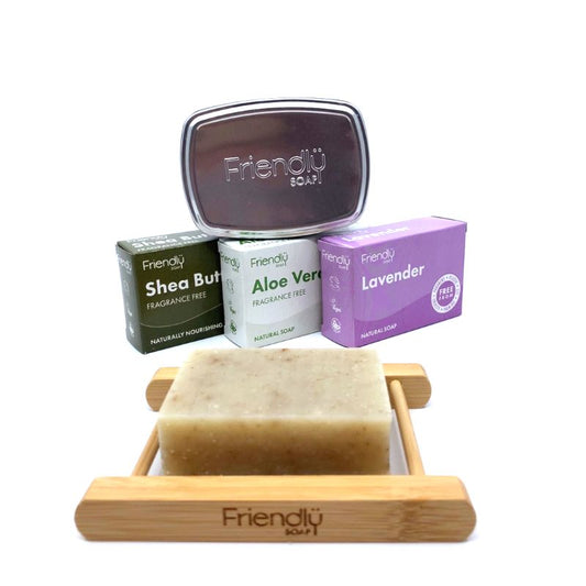 A set of bar soaps with packaging, including a natural soap bar, bamboo soap rack, and a travel tin with a drip tray, all branded 'Friendly', arranged on a white background.