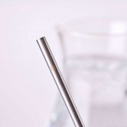 Close-up of a Stainless Steel Drinking Straws (singles) with a blurred glass of water in the background.