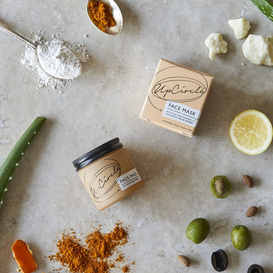 UpCircle face mask jar and box on a textured surface with natural ingredients