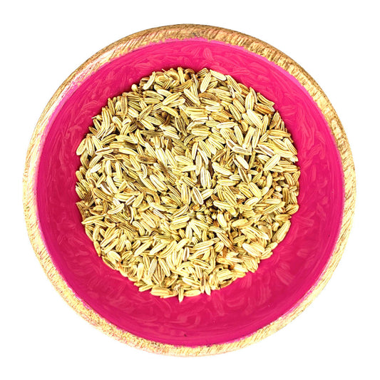 Pink bowl with gold rim filled with fennel seeds on a white background