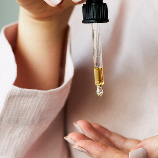 Close-up of a dropper with a drop of liquid held by a person.