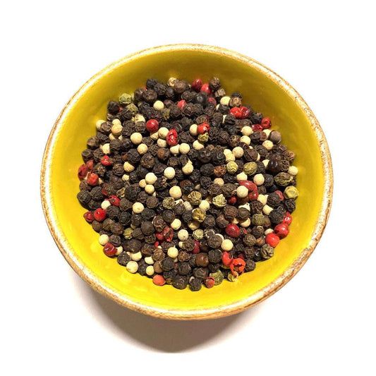 Yellow bowl filled with multicolored peppercorns on a white background