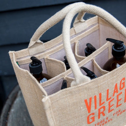 Jute bottle bag with compartments holding refillable pump bottles for plastic free household essentials.